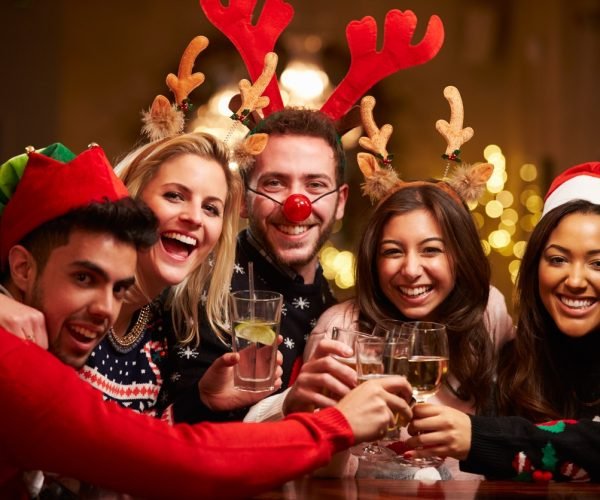 Group Of Friends Enjoying Christmas Drinks In Bar Smiling To Camera
